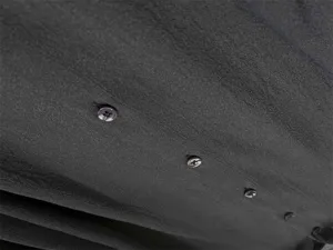 Close-up detail of dark grey sheer organza blouse fabric showing fine delicate buttons texture.
