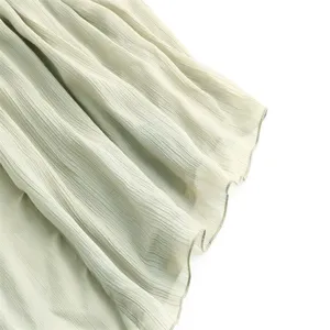 Detailed view of light green pleated midi skirt fabric with delicate lettuce edge.