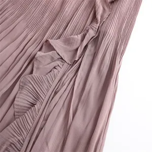 Close-up detail of pleated skirt fabric with delicate ruffles and split design in dusty pink.