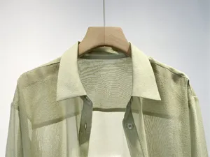 Close-up detail of light green sheer organza shirt collar and button placket design.