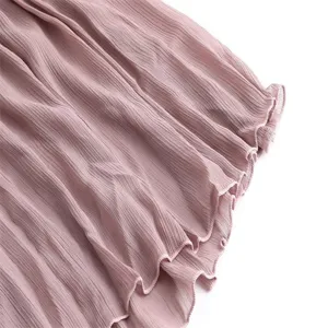 Close-up detail of dusty pink pleated skirt fabric featuring a delicate lettuce edge hem.