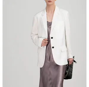 Close-up detail toont de gladde textuur en getailleerde pasvorm van de witte blazer.