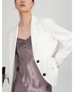 Witte blazer en donkergrijze satijnen top gecombineerd met elegante parel sieraden.