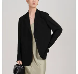 Dames zwarte blazer gecombineerd met groen satijnen slipdress, detailweergave stijl.
