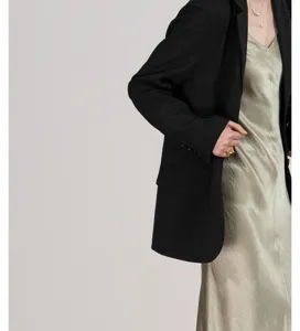 Stijlvolle zwarte damesblazer gecombineerd met glanzende slipdress detailweergave
