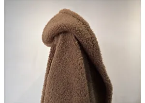 Brown teddy fleece hooded coat detail, cozy thick wool texture, warm winter garment close up.