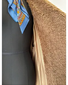 Detail view of brown curly teddy fleece coat, soft silky lining and stylish blue scarf accent.