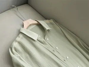Detailed shot of a light green sheer organza button-up shirt, fine texture and collar view.