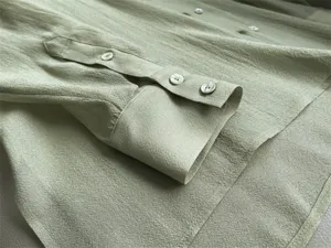 Close-up detail of light green acetate organza shirt cuff and buttons, elegant translucent texture.
