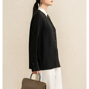 Detailed shot of women's black long sleeve blouse with contrast white collar, elegant look.