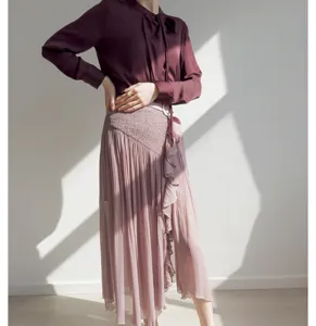 Close-up detail of pleated midi skirt with ruffle split and matching burgundy blouse outfit.