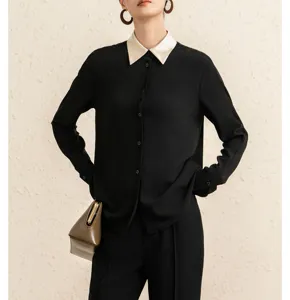 Detailed view of a chic black long sleeve blouse featuring an elegant contrast white collar.