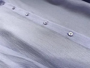 Close up detail of light purple acetate organza shirt button placket and fabric texture.