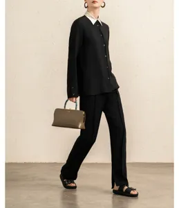 Detailed view of luxury black contrast collar blouse with elegant handbag.