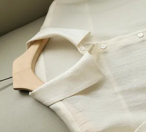Close-up detail of sheer acetate organza shirt collar and small buttons on hanger.