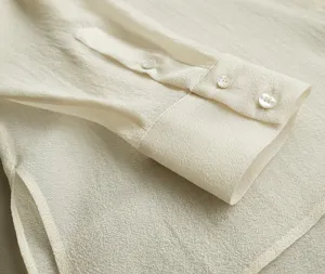 Close-up of delicate long sleeve cuff with neat buttons, translucent organza fabric detail.