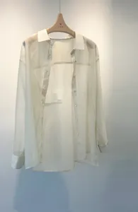 Detailed shot of a sheer lightweight button-down shirt hanging elegantly on a wooden hanger.