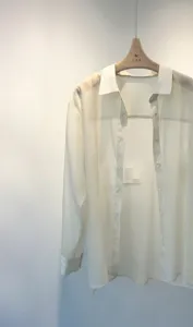 Detail view of a sheer white long sleeve blouse, lightweight organza shirt, minimalist casual wear.