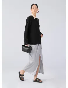 Detail view of the elegant black long sleeve blouse and grey slit skirt worn by model.