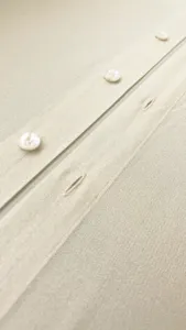 Detailed view of women's shirt placket with white buttons and smooth translucent organza fabric.