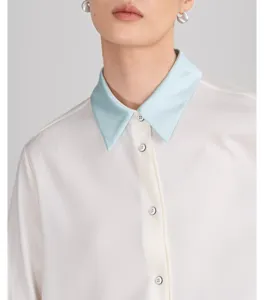 Close up view of luxury white silk shirt with contrast light blue collar and pearl buttons.
