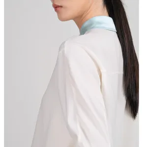 Elegant white silk-blend blouse featuring a contrasting light blue collar detail close-up.