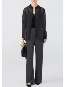Sheer black organza button-down shirt paired with grey wide-leg pants and stylish handbag.