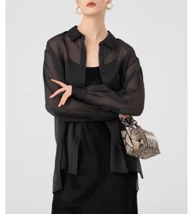 Detailed shot of a black sheer organza shirt paired with a snakeskin chain handbag.