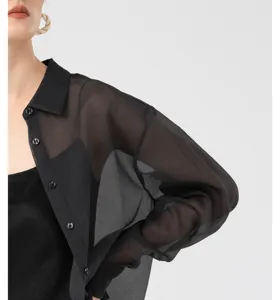 Detailed view of women's black sheer long sleeve organza button down shirt and inner top.