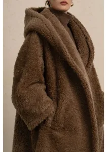 Detail view of a cozy brown teddy coat featuring soft plush texture, oversized hood and warm knit.