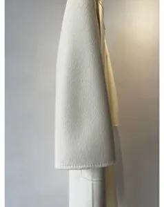 White cashmere coat fabric detail shot, showing exquisite water ripple texture and premium wool blend.