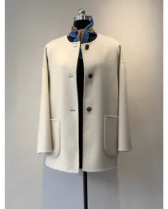 Détail de manteau en laine minimaliste, col rond avec poches et écharpe élégante.