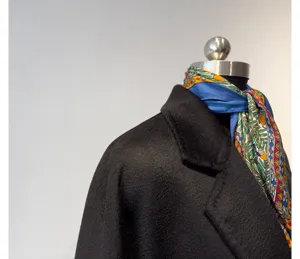 Black cashmere blend long coat detail view with elegant patterned silk scarf accessory.