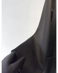 Detailed close-up view of dark cashmere wool fabric texture with water ripple pattern for winter coat.
