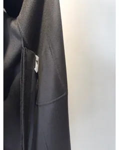 Close-up detail of luxury cashmere wool blend long coat fabric texture and pocket design.