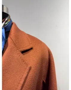 Detail view of a luxury rust cashmere bathrobe coat, highlighting fine collar and texture.