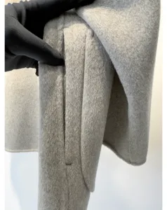 Gros plan de la poche du manteau en laine cachemire grise, texture fine, style élégant.