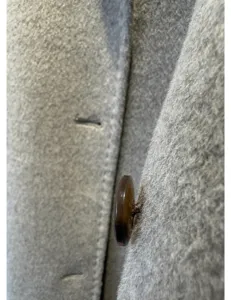 Gros plan détaillé de la texture du tissu de manteau en cachemire de laine grise et beau bouton.