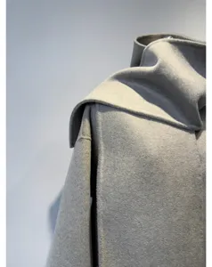 Détail rapproché du manteau en laine et cachemire gris avec écharpe intégrée et élégante.