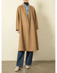 Detailed view of the elegant camel cashmere long coat showcased with chic denim outfit.
