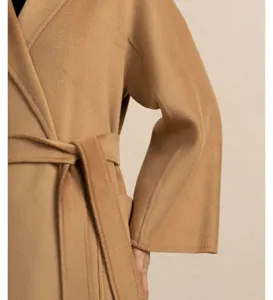 Close-up detail shot of a luxury camel cashmere wrap coat featuring a matching belt and soft texture.