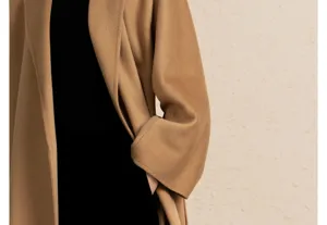 Detail shot showing the exquisite camel cashmere blend wrap coat with lapel and pocket design.