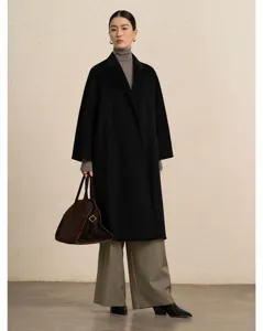 Detail shot of women black cashmere long coat paired with grey trousers and suede bag.