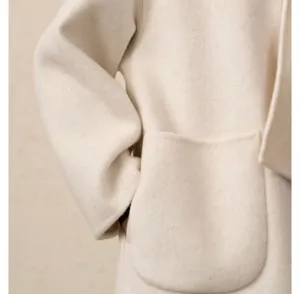 Détail de manteau en laine et cachemire avec grande poche et manche en beige neutre.