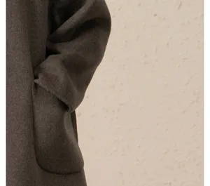 Détail en gros plan de la manche et poche du luxueux manteau cachemire marron foncé.
