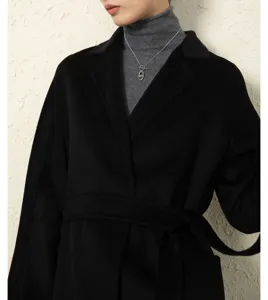 Detailed shot of women's black cashmere robe coat with grey turtleneck and silver anchor chain.