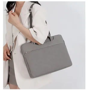 Vista dettagliata dell'elegante borsa per laptop grigia con manici e tracolla per l'ufficio.