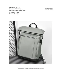 Close-up of gray business backpack with roll-top design, front zipper pocket and side slots.