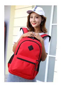 Detail view of a red canvas backpack worn by a model outdoors, featuring durable zippers.