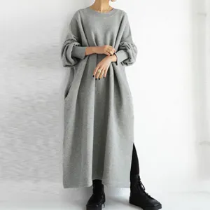 Detail shot of the loose grey sweatshirt dress, showcasing side slit and long sleeves.